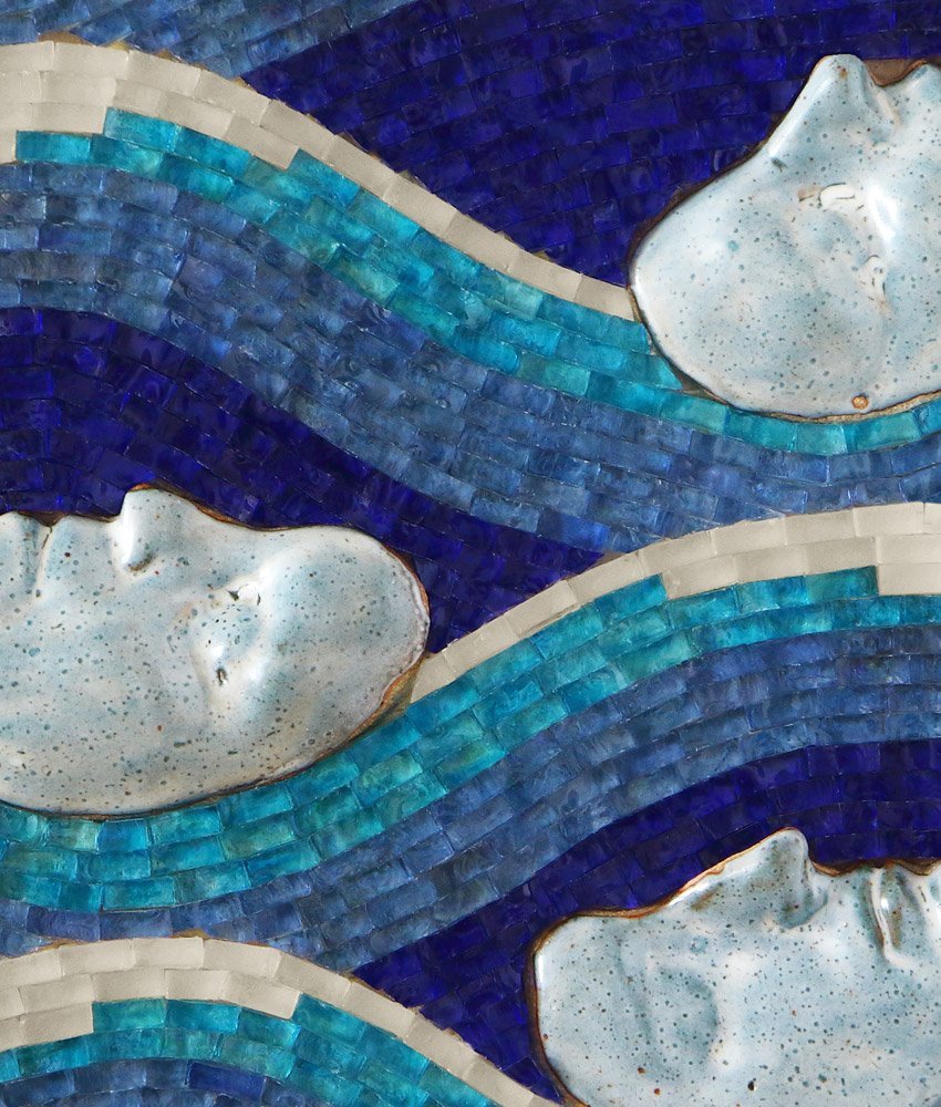 Close up detail of Caryn Mitchell’s Float, 16 x 20, mixed media wall artwork made of cobalt blue, sea blue, ocean blue, frosted white glass mosaic and four life-casted stoneware fired faces
